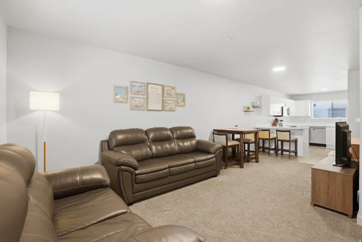 Open-concept living area with neutral carpeting and white walls