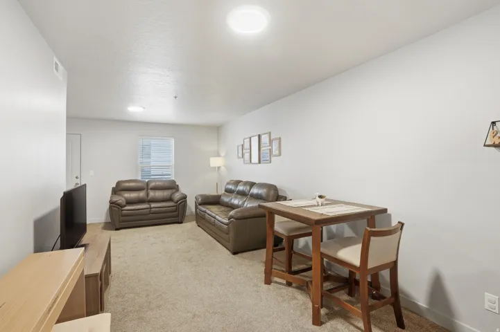 Living area featuring plush carpeting, light neutral wall tones, and recessed ceiling lighting