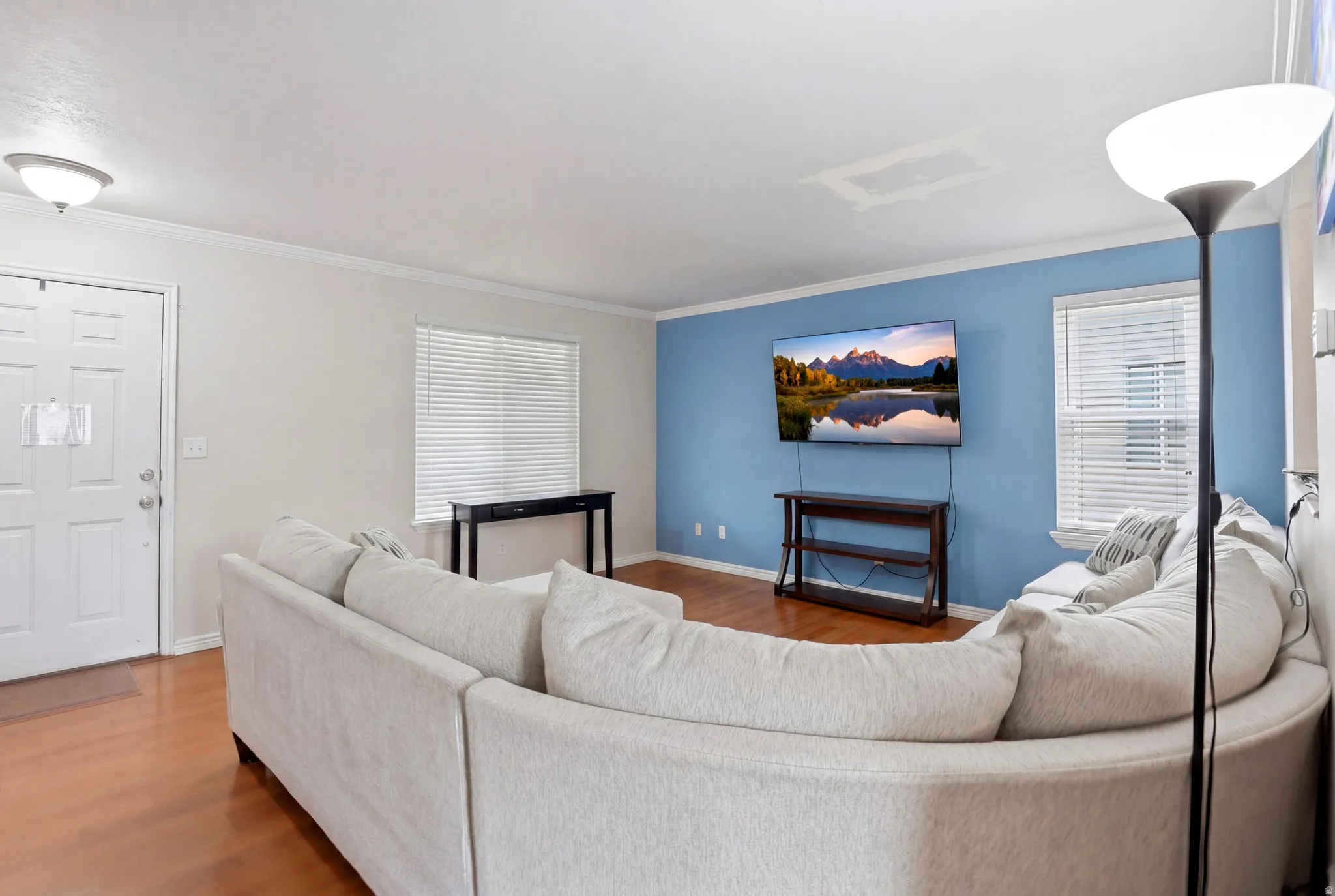 Living area featuring wood-finish flooring, white trim, and a prominent accent wall