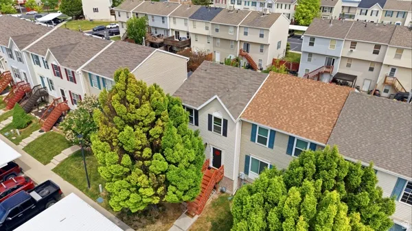 Two-story townhouse with light-toned siding, dark shutters, and a front entry stairwell