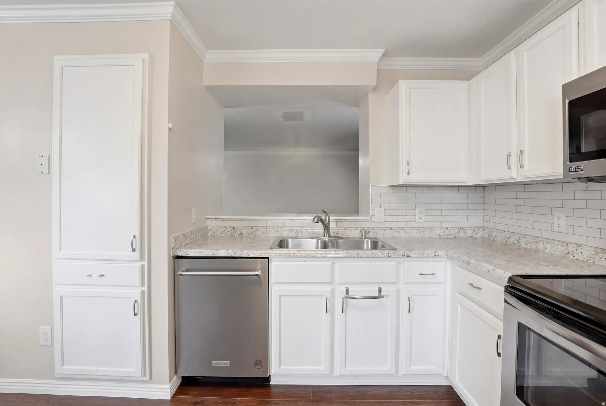 Kitchen featuring white cabinetry, granite-finish countertops, stainless steel appliances, a subway tile backsplash, and wood-finish flooring