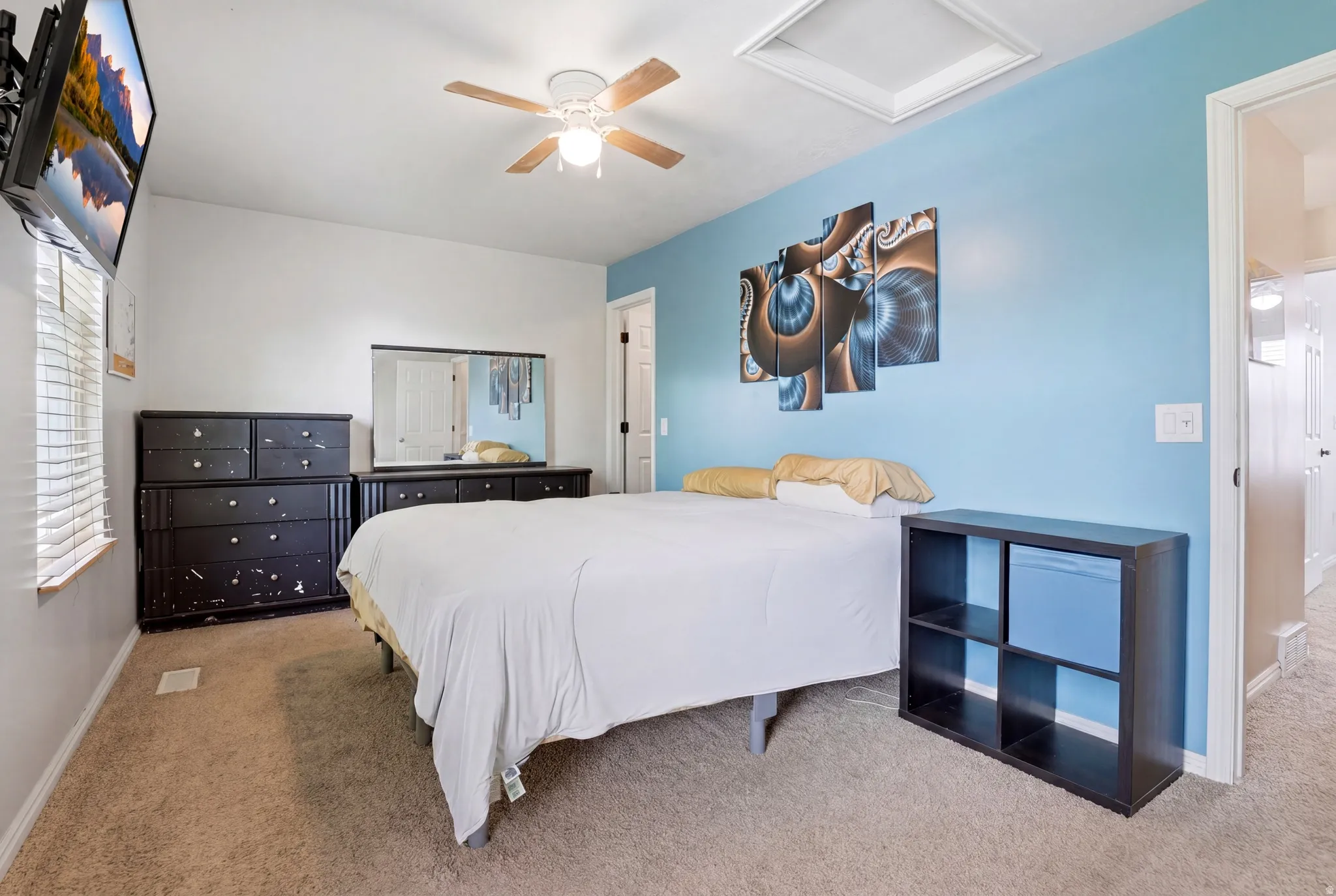 Carpeted bedroom featuring a light blue accent wall, white window blinds, and a ceiling fan