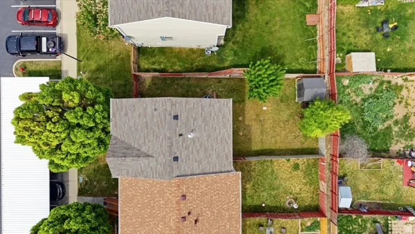 Aerial perspective showcasing multiple residential properties, fenced yards, and mature trees