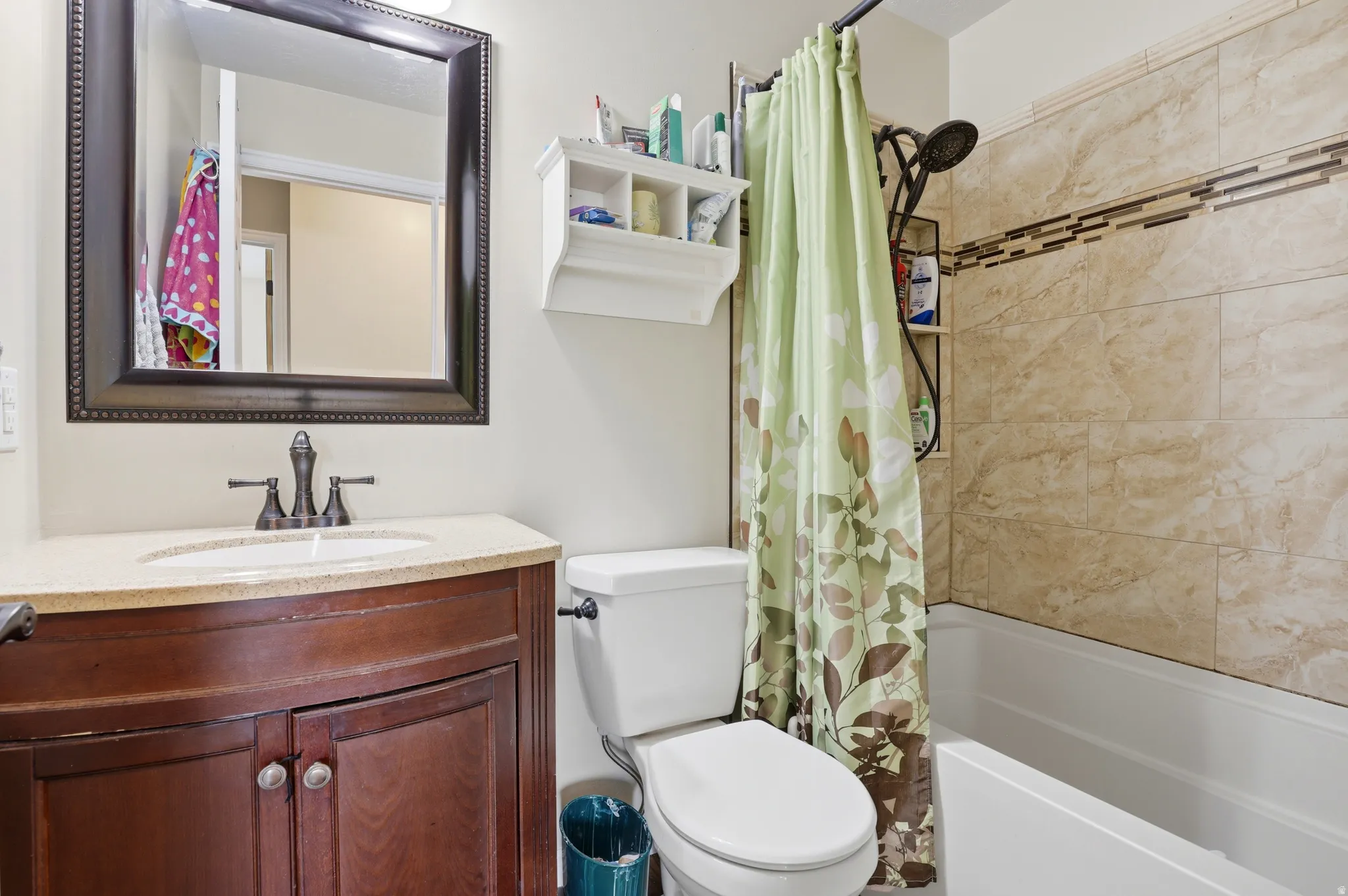 Bathroom featuring a dark wood-finish vanity with a light-colored countertop, an oval undermount sink, and a framed mirror