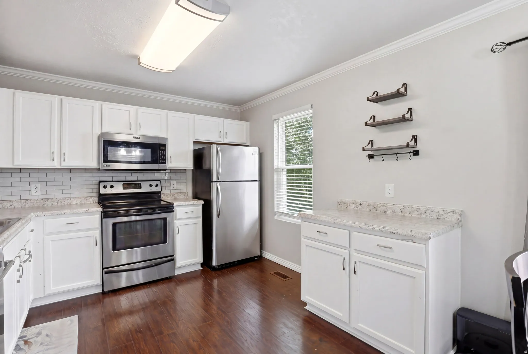 Kitchen featuring white cabinetry, stainless steel appliances, speckled countertops, and wood-finish flooring