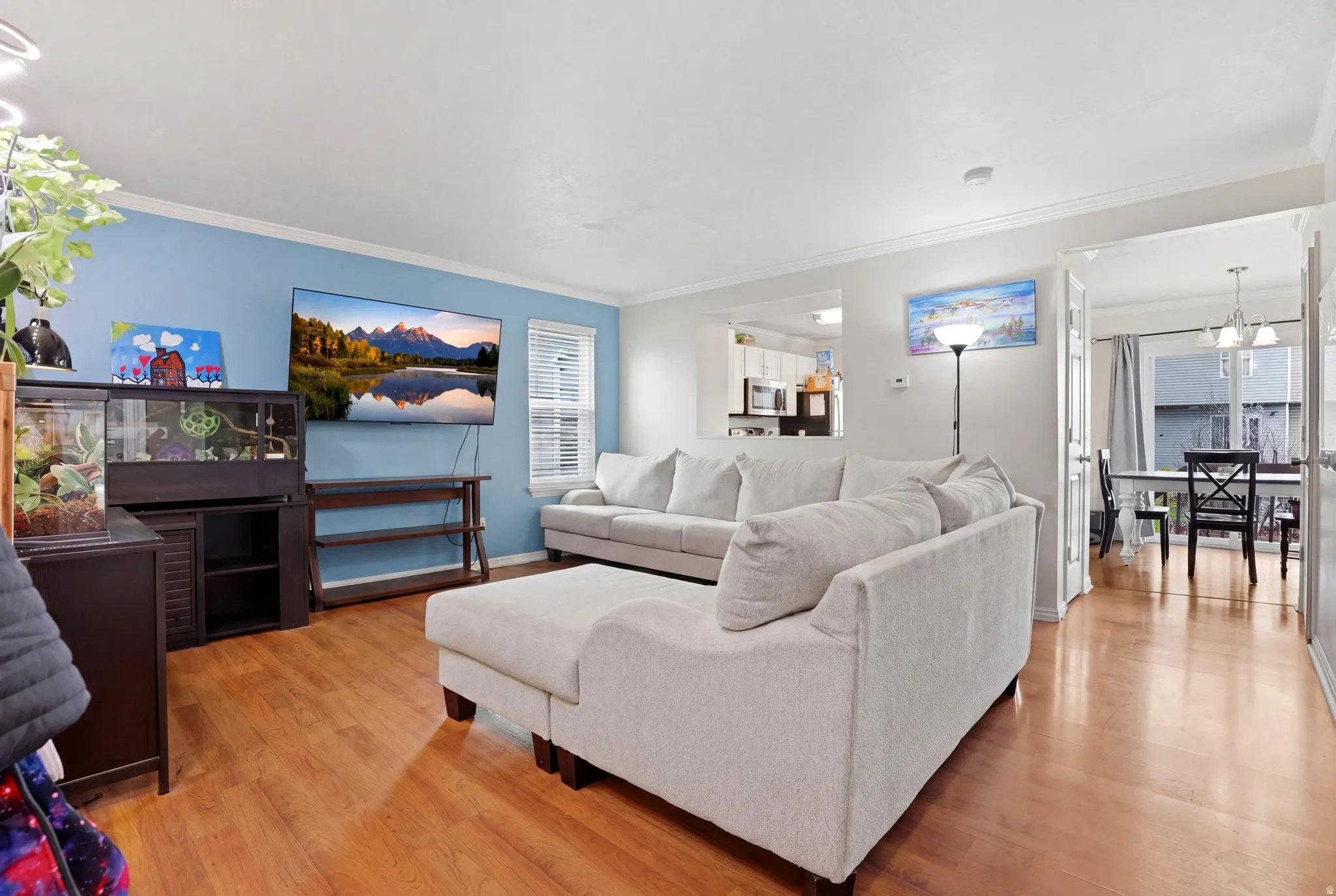 Open-concept living area featuring wood-finish flooring and crown molding
