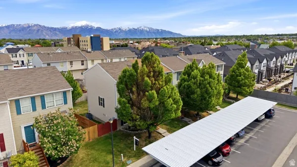Townhome community featuring a multi-level structure, a covered parking area, and mature landscaping