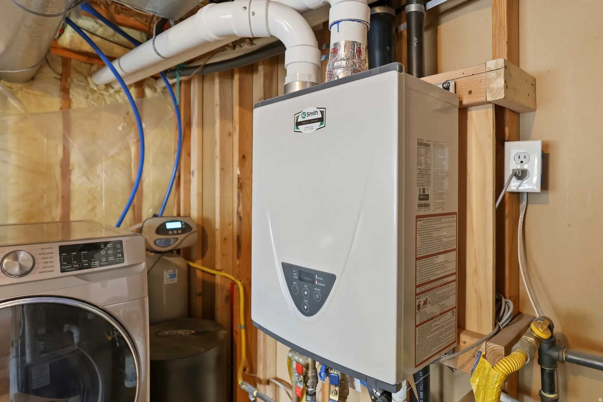 Tankless water heater installation with exposed wood framing and utility connections