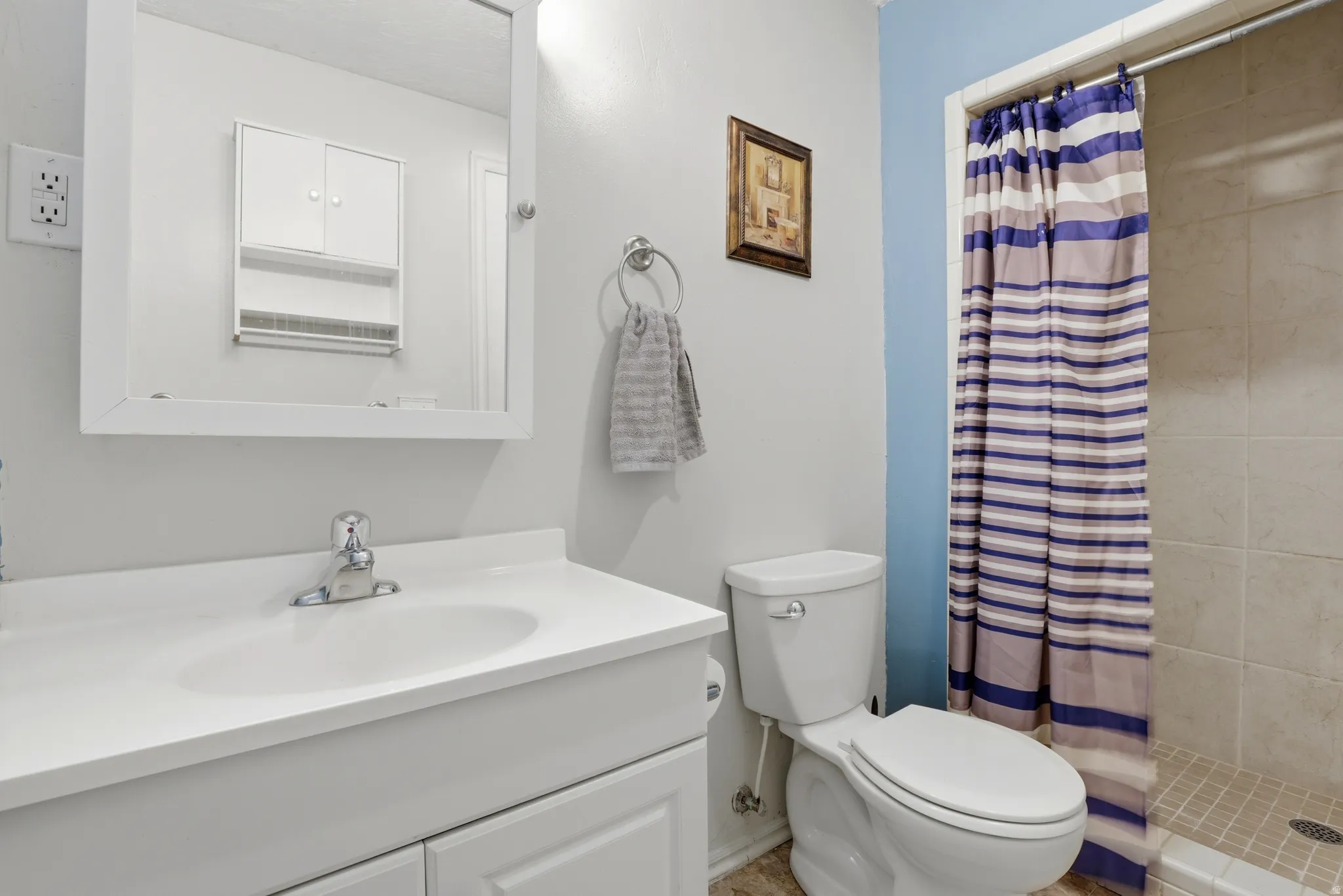 Bathroom featuring a white vanity with integrated sink, coordinating wall mirror, and an adjacent toilet