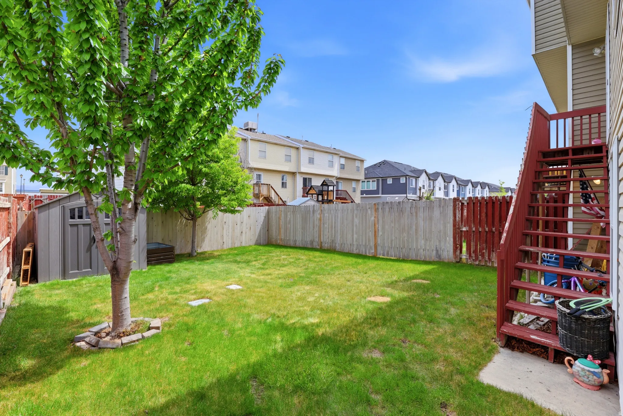 Private fenced yard featuring a storage shed and mature trees