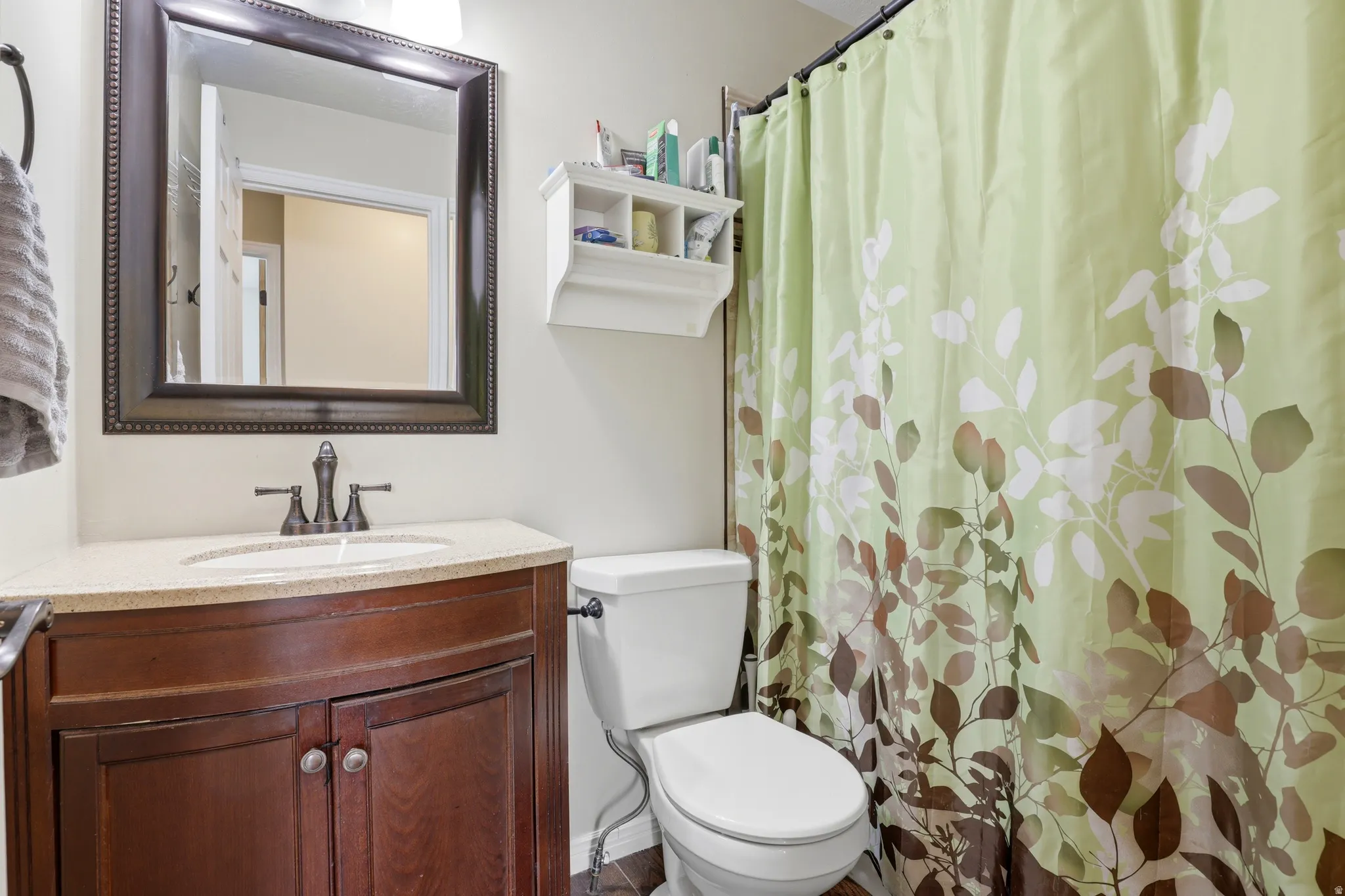 Bathroom vanity featuring a granite-style countertop, a dark wood-finish cabinet with curved doors, a rectangular undermount sink, and an oil-rubbed bronze faucet