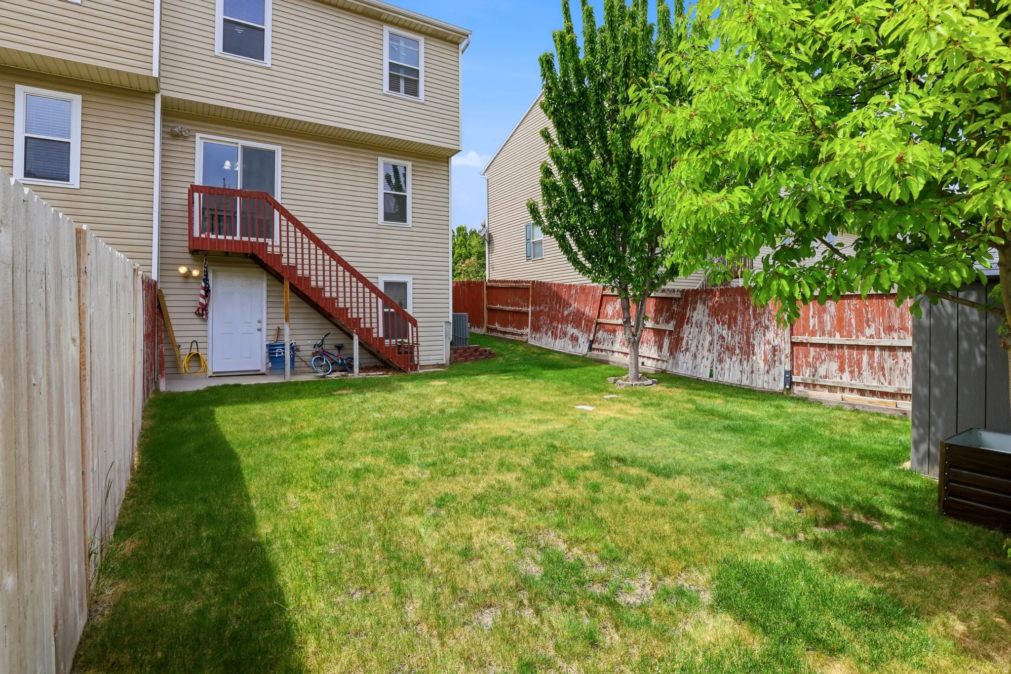 Expansive green lawn with a privacy fence and mature trees