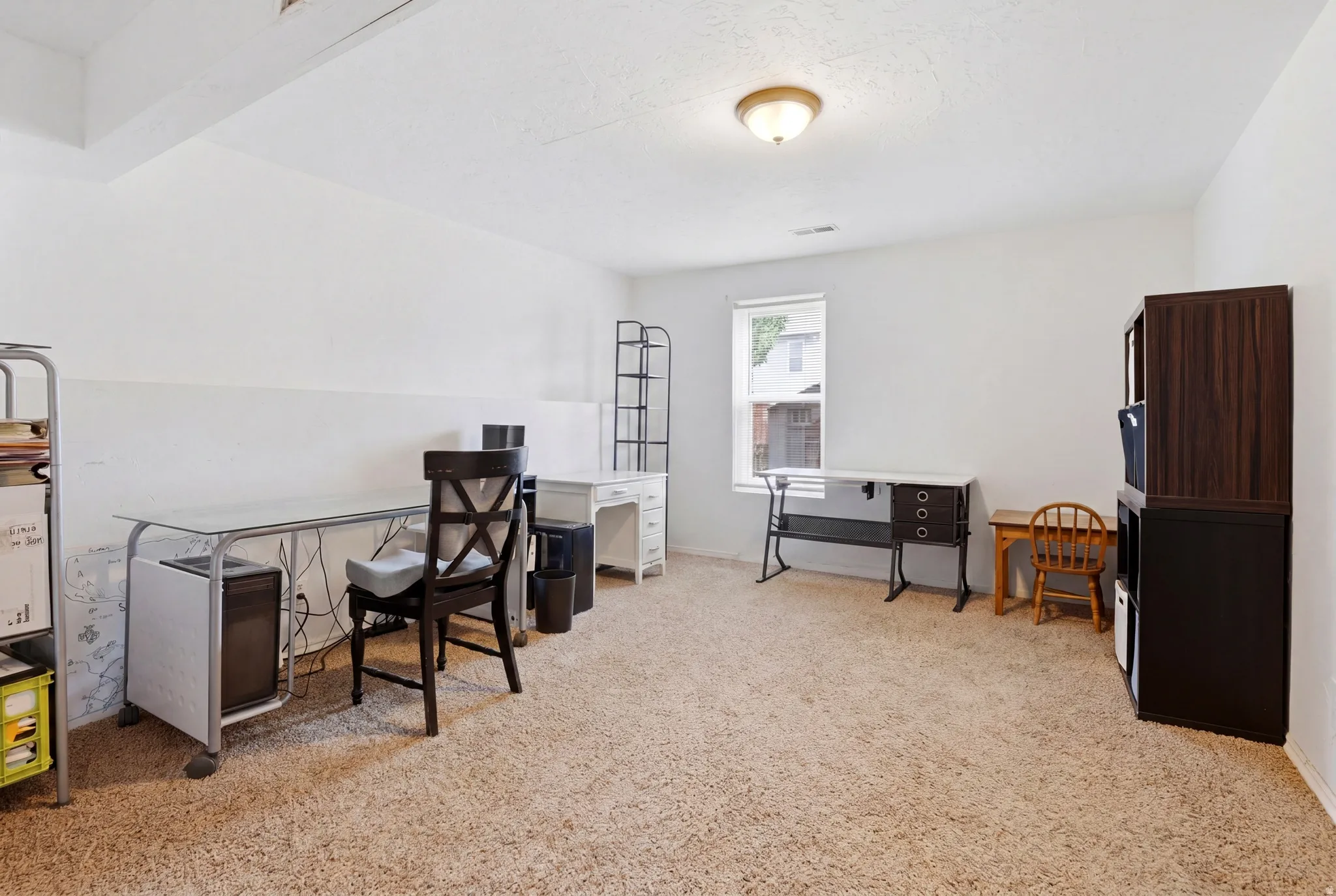 Spacious room featuring neutral carpeting, white walls, and a single window allowing natural light