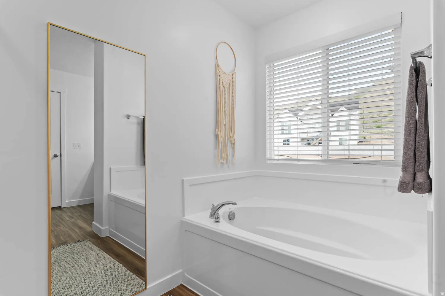 Built-in bathtub with chrome fixtures and a window featuring horizontal blinds