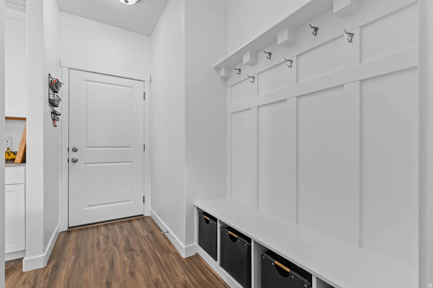 Mudroom featuring built-in white board and batten wall paneling, integrated bench seating, and wood-finish flooring