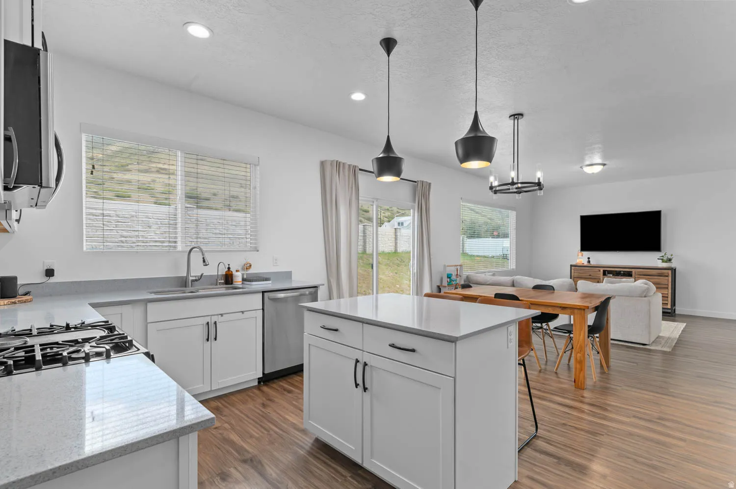 Kitchen featuring white cabinetry, light-toned countertops, a stainless steel gas cooktop, and a center island