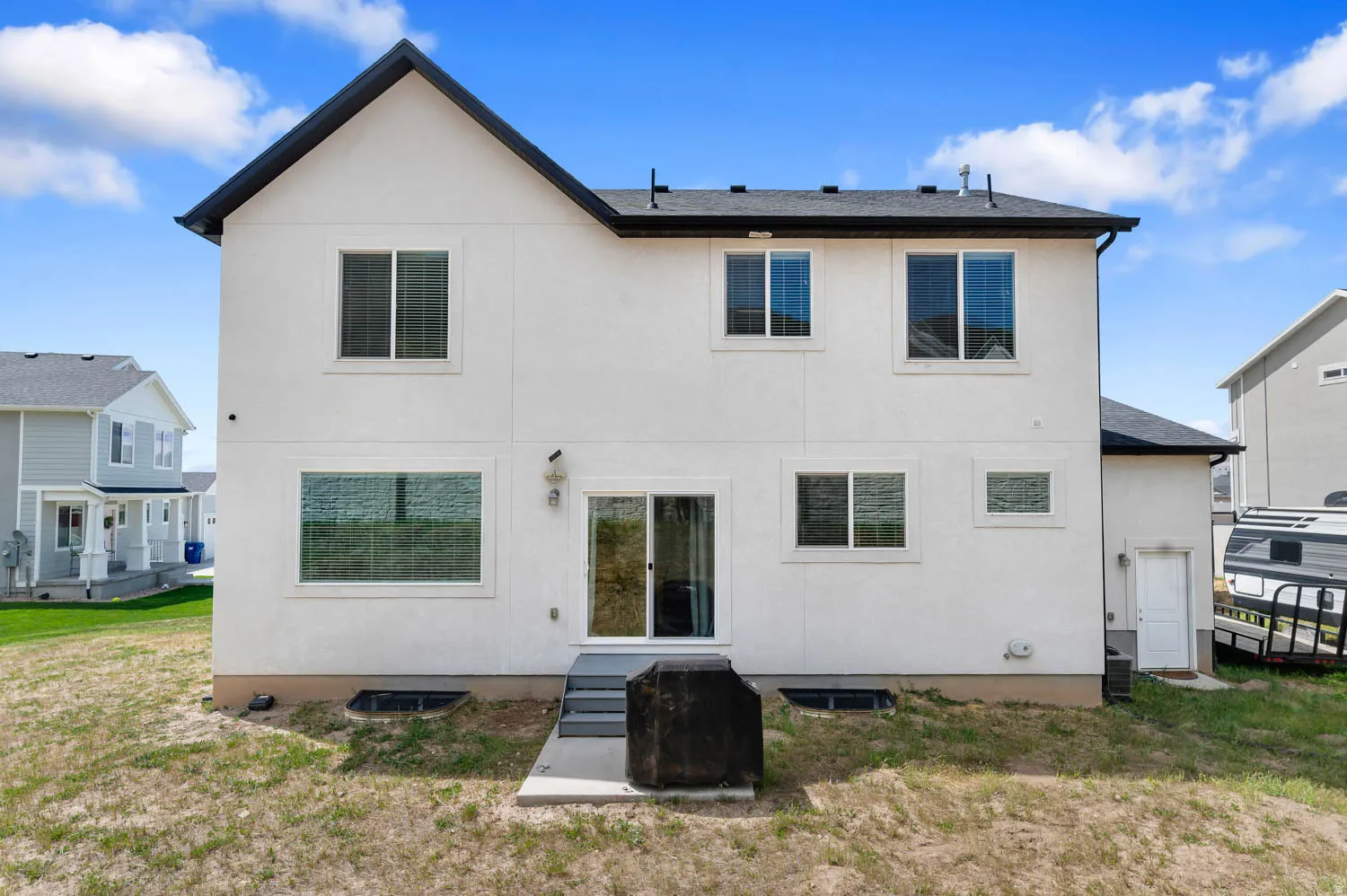 White stucco exterior featuring a gabled roofline and multiple windows