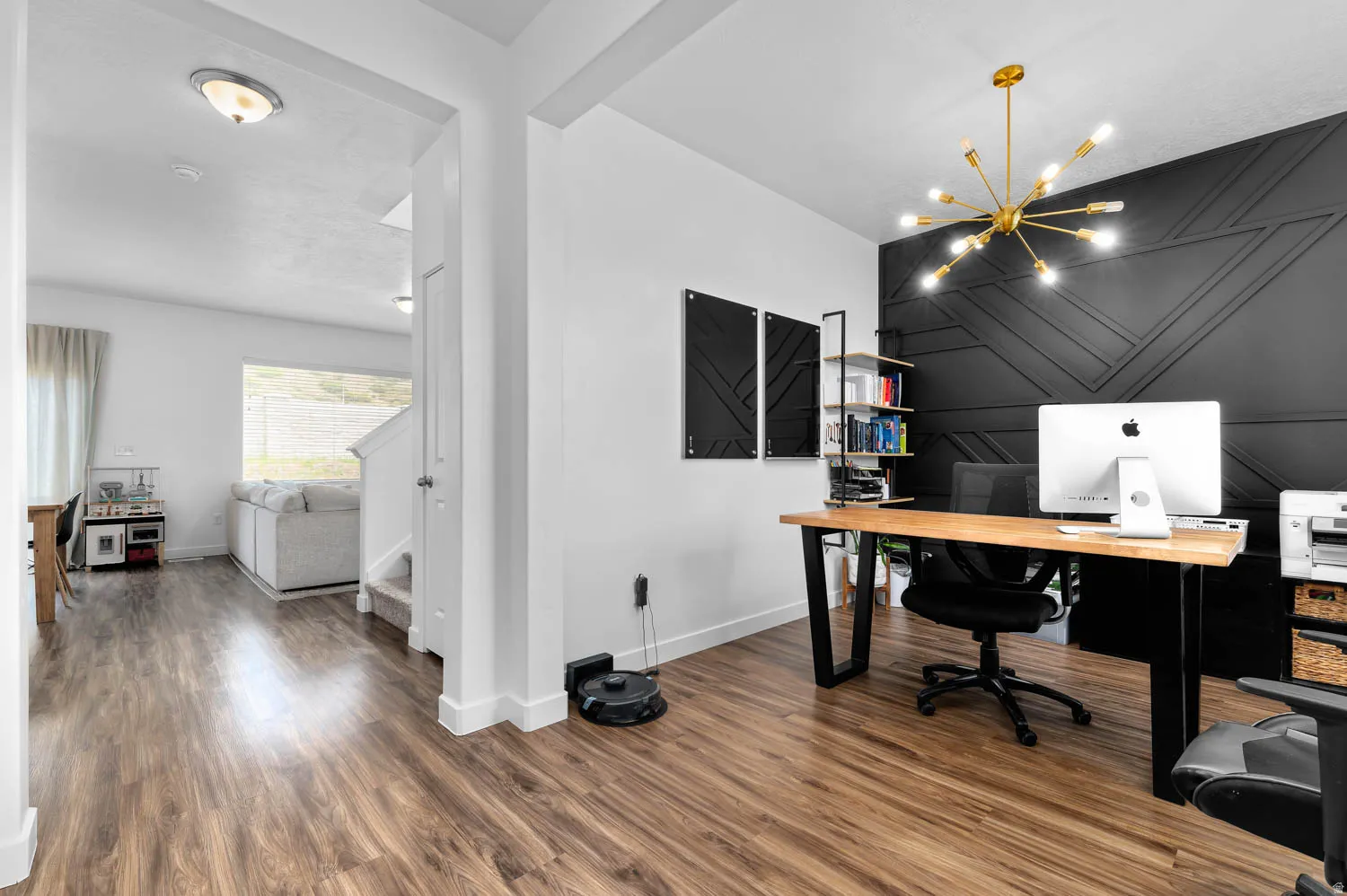 Dedicated office space featuring a geometric accent wall, wood-finish flooring, and a modern sputnik chandelier