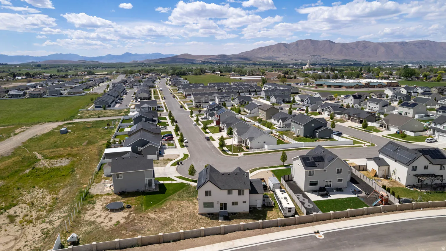 Aerial perspective showcasing a residential community with contemporary homes, mountain backdrop, and clear sky