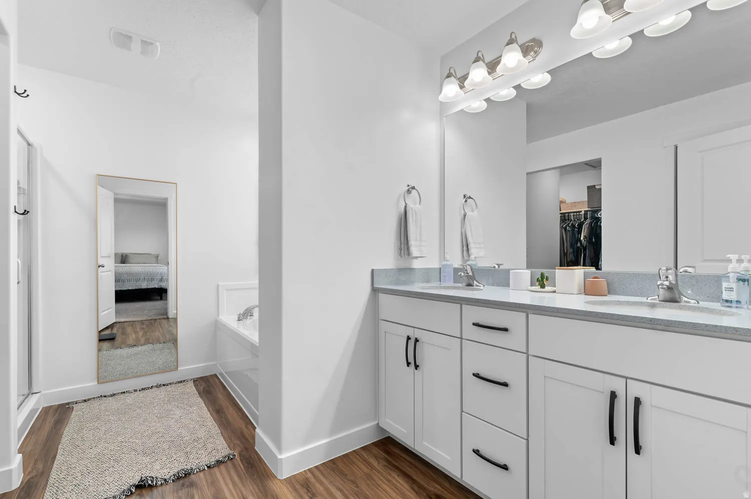 Dual vanity with white cabinetry, matte black hardware, and light-toned countertops