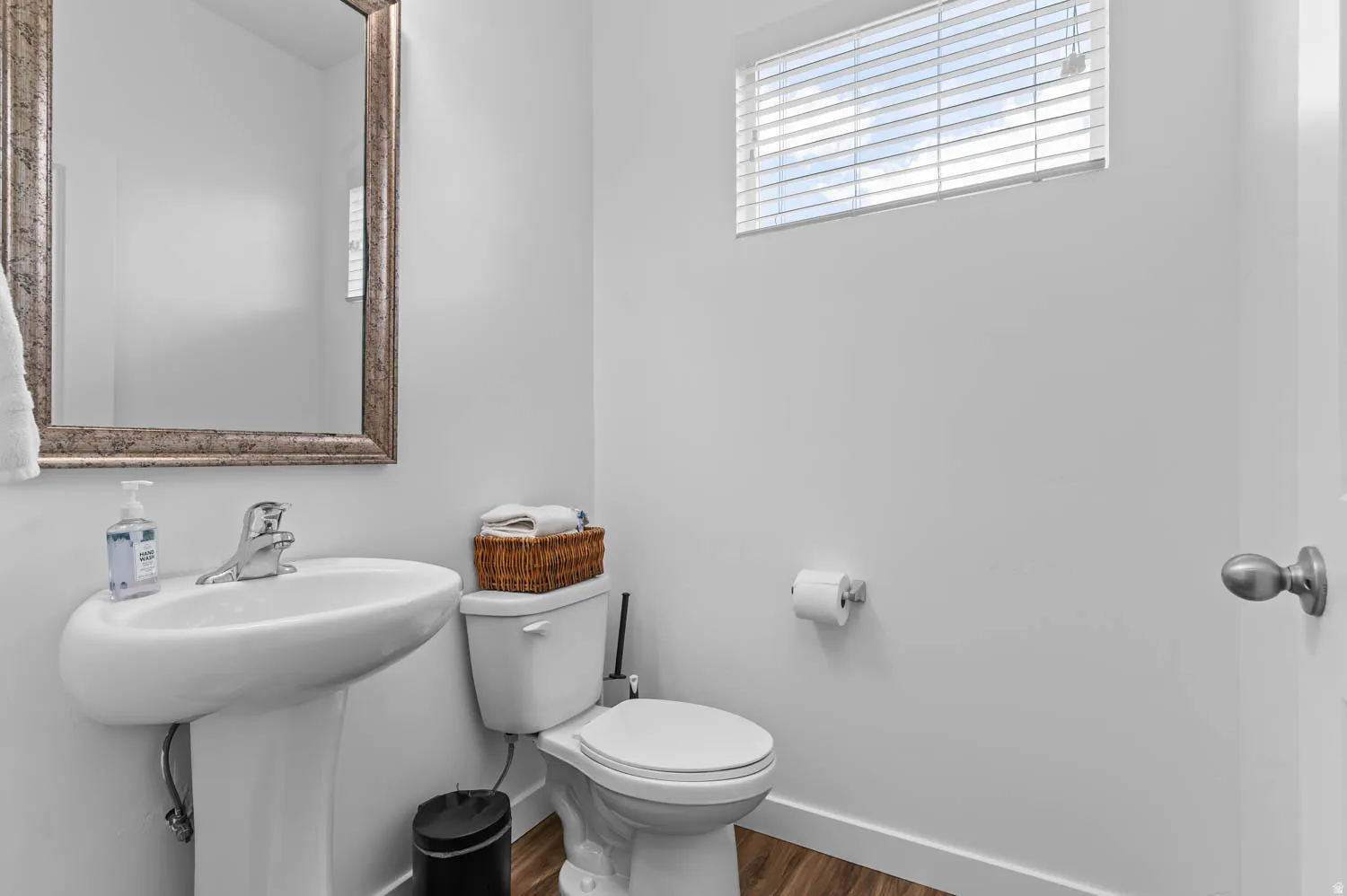 Pedestal sink with chrome faucet and a decorative framed mirror