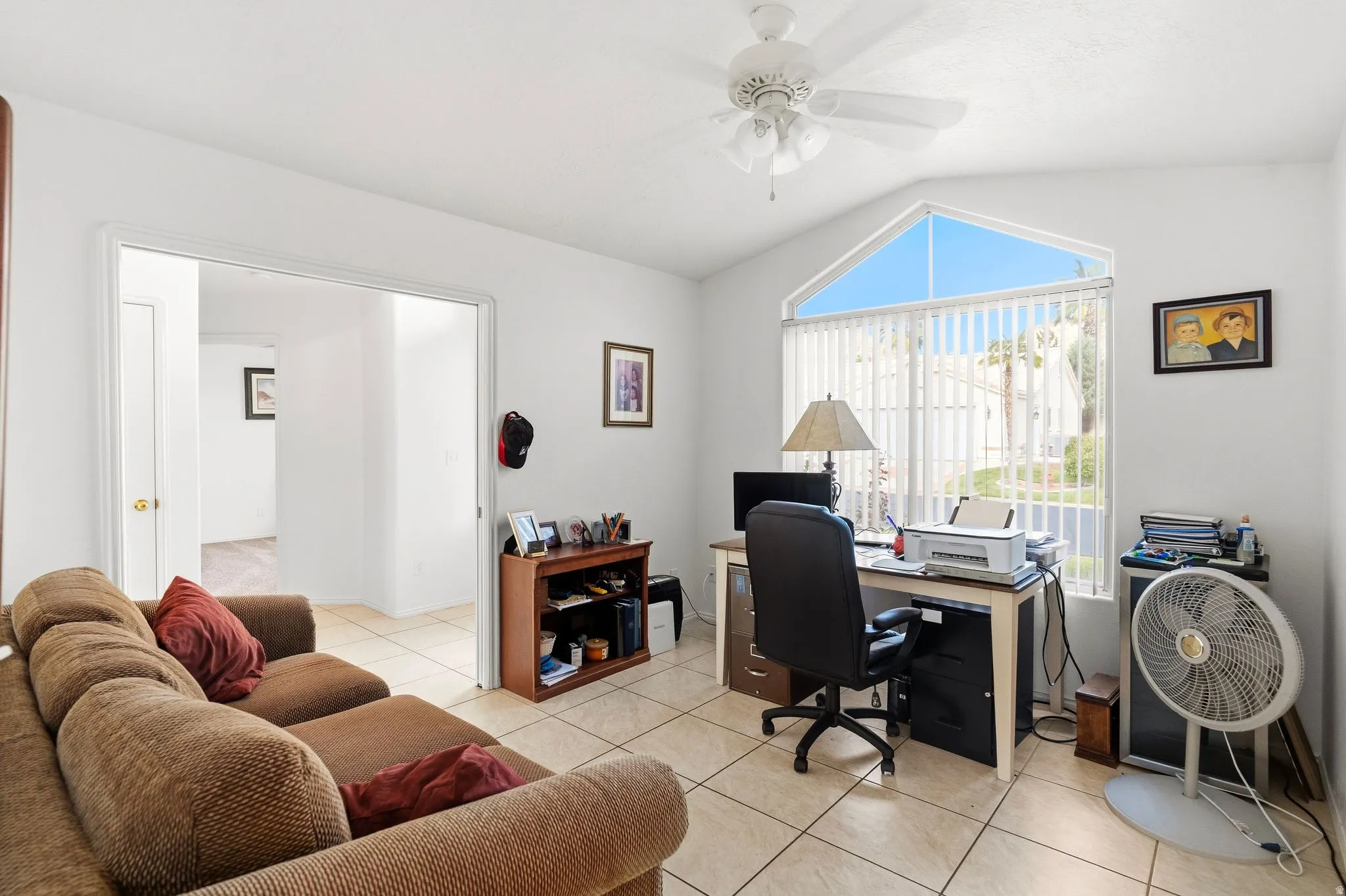 Vaulted ceiling with an architectural window, ceiling fan, and tile flooring