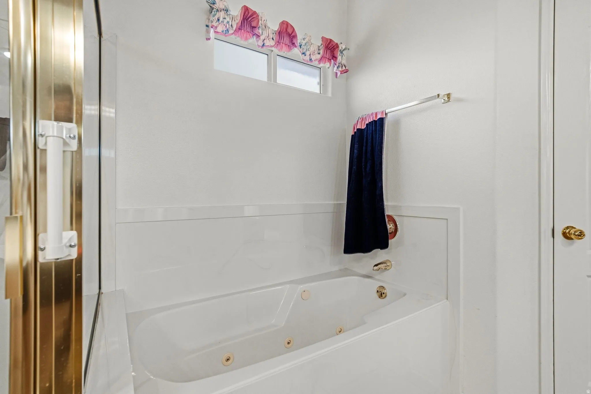Jetted soaking tub with a white surround and gold-tone fixtures