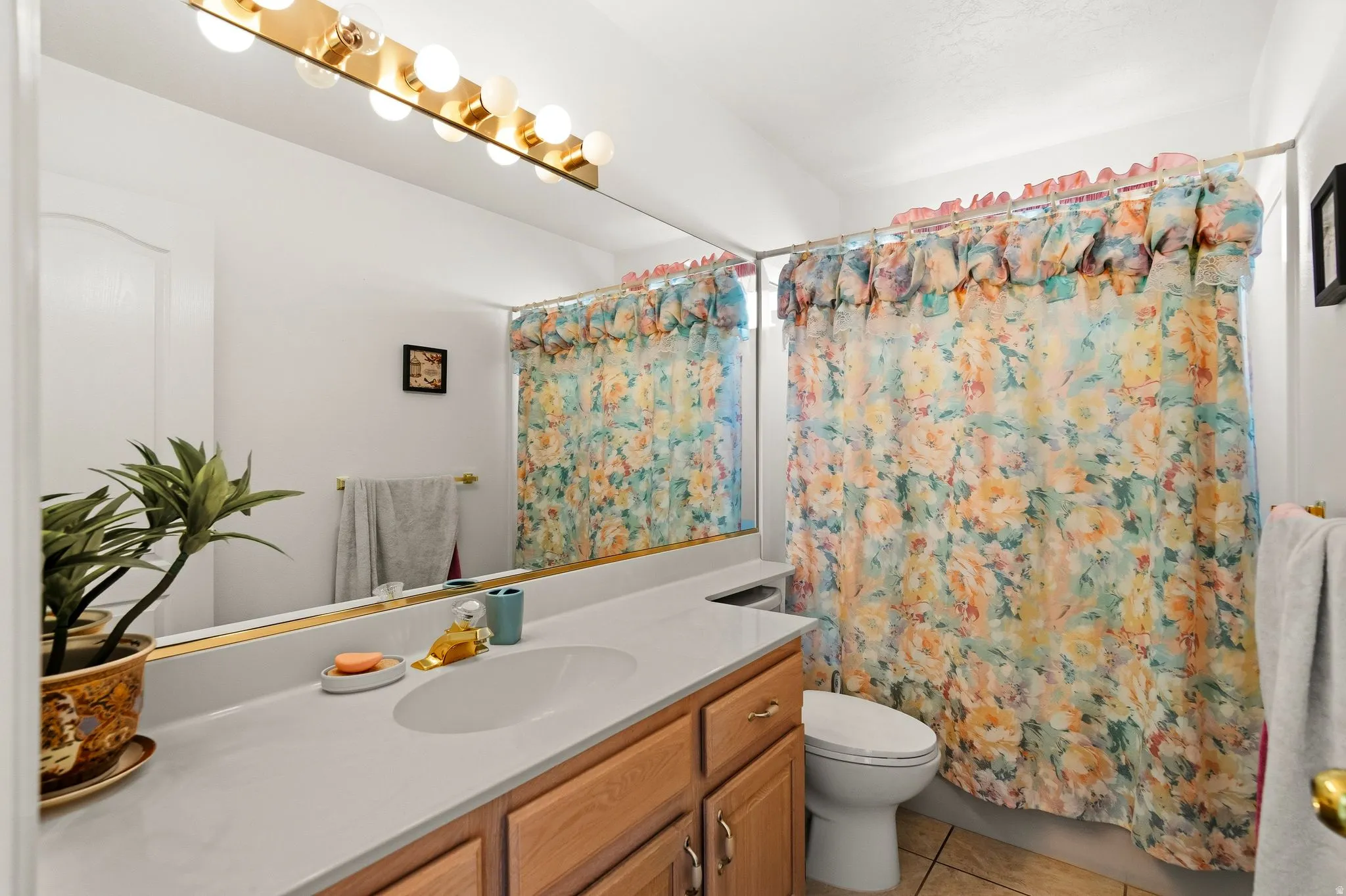 Full-width vanity mirror with an integrated light bar, a single-basin sink, and natural wood-finish cabinetry