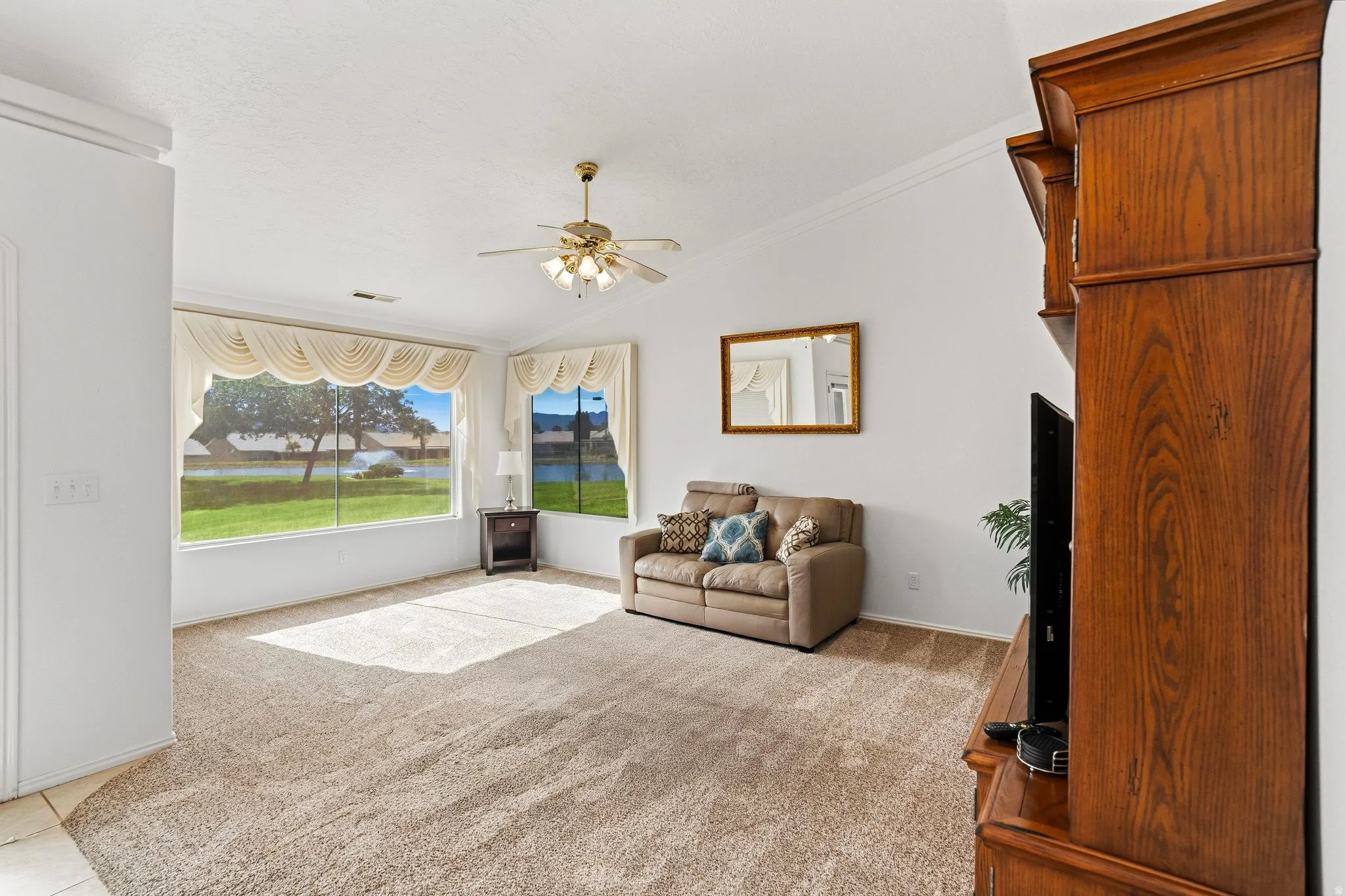 Spacious living area featuring expansive windows, neutral tone carpeting, and a built-in media cabinet