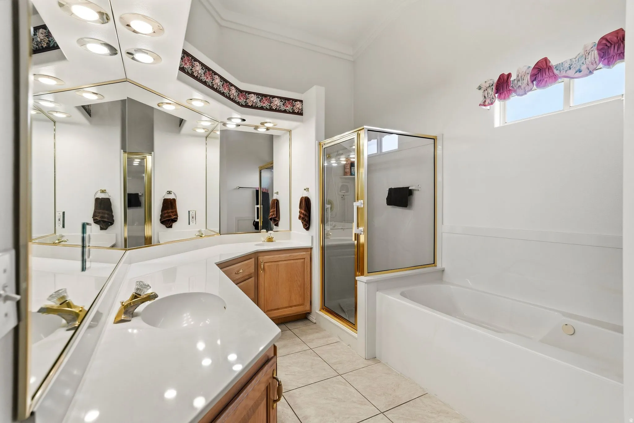 Bathroom featuring a dual vanity with light-toned countertops, integrated sinks, and brass-finish fixtures