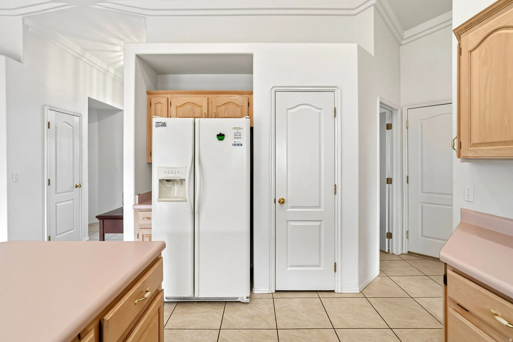 Kitchen space featuring light wood-finish cabinetry, tile flooring, and light-toned countertops
