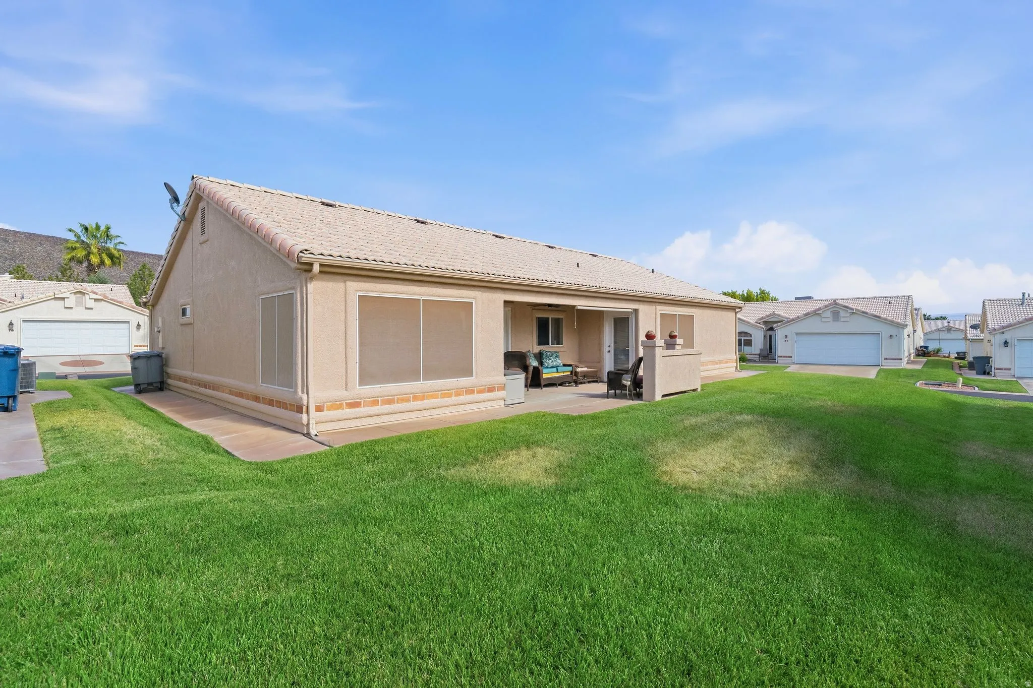 Expansive grassy area with a stucco exterior featuring a tiled roof