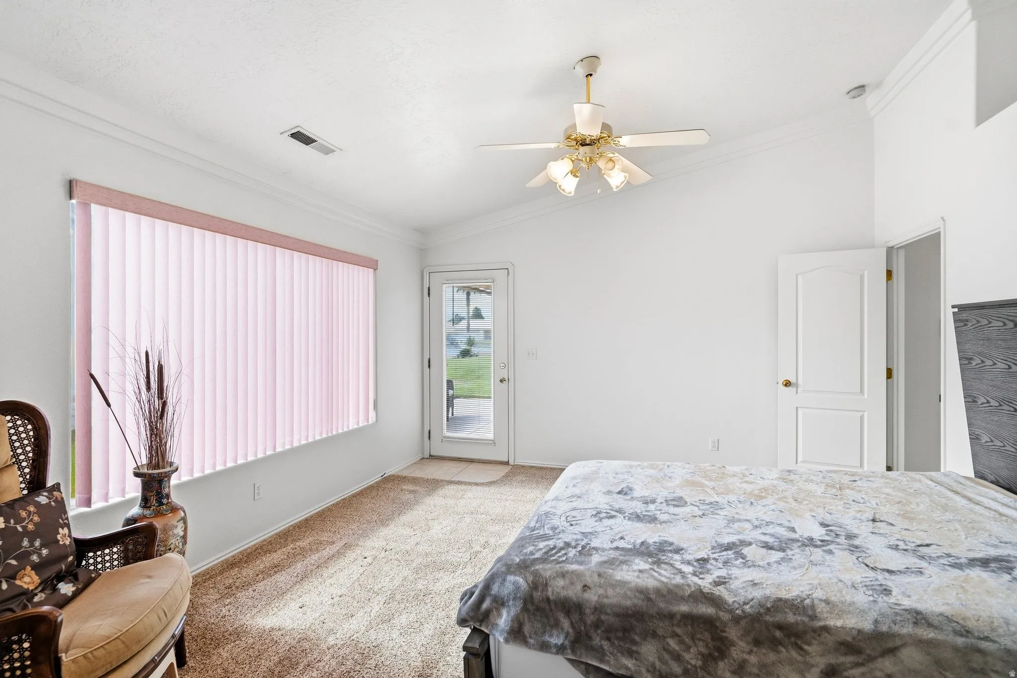 Carpeted room featuring a ceiling fan with integrated lighting, vaulted ceiling, and a glass-paneled exterior door