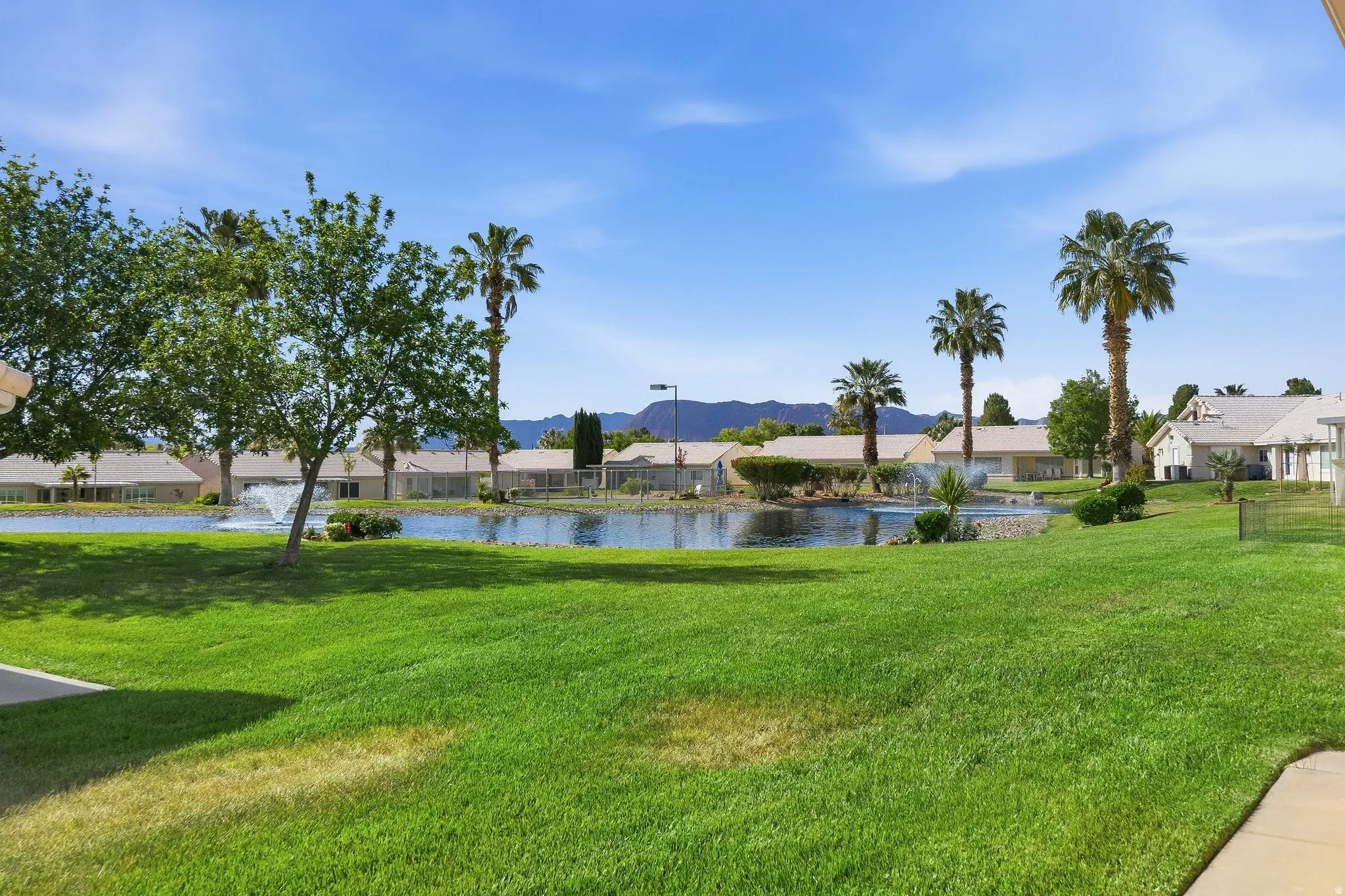 Expansive green lawn bordering a tranquil pond with a fountain