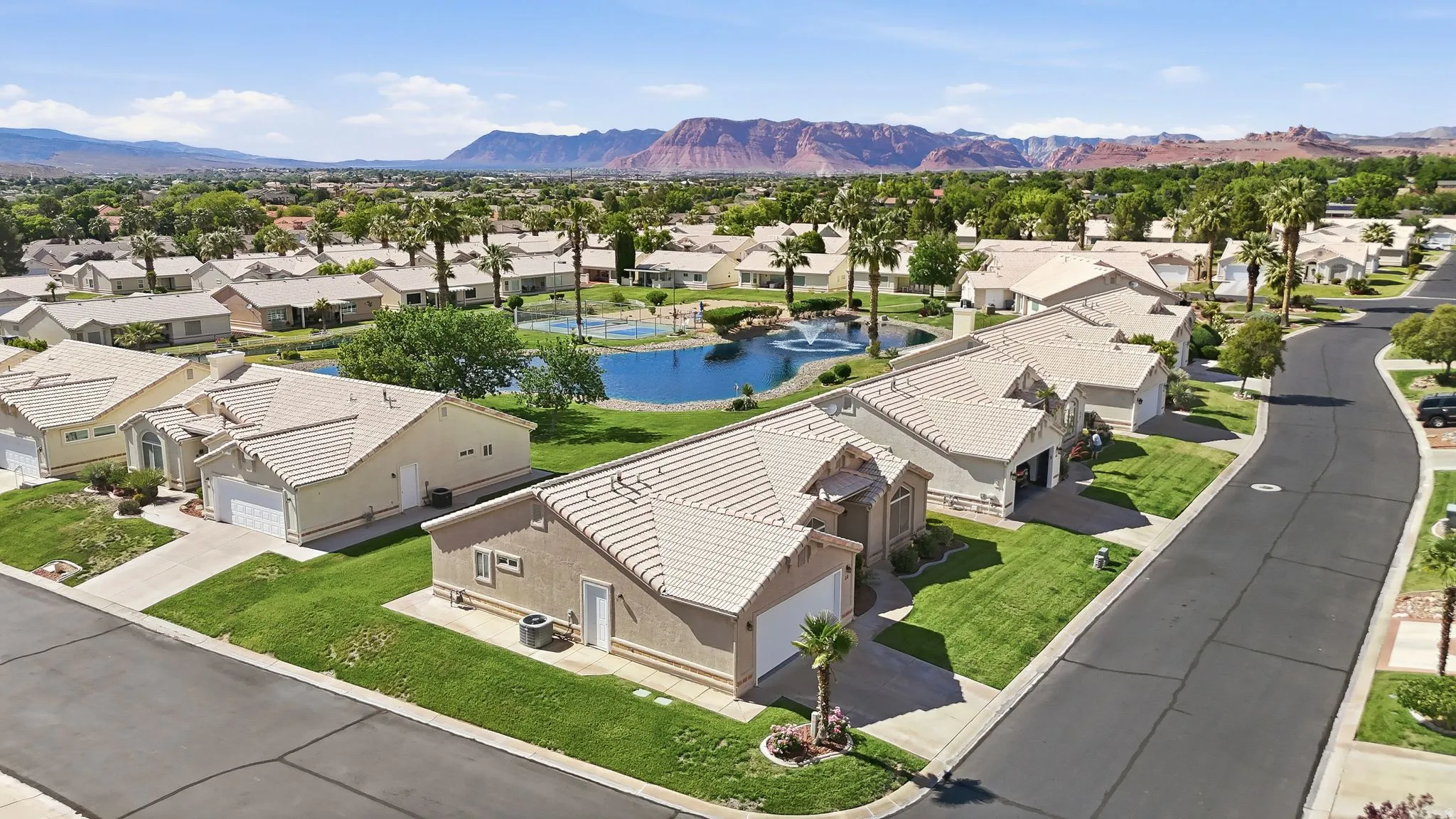 Aerial perspective of a residential neighborhood featuring single-story homes with light-colored tile roofs and manicured lawns