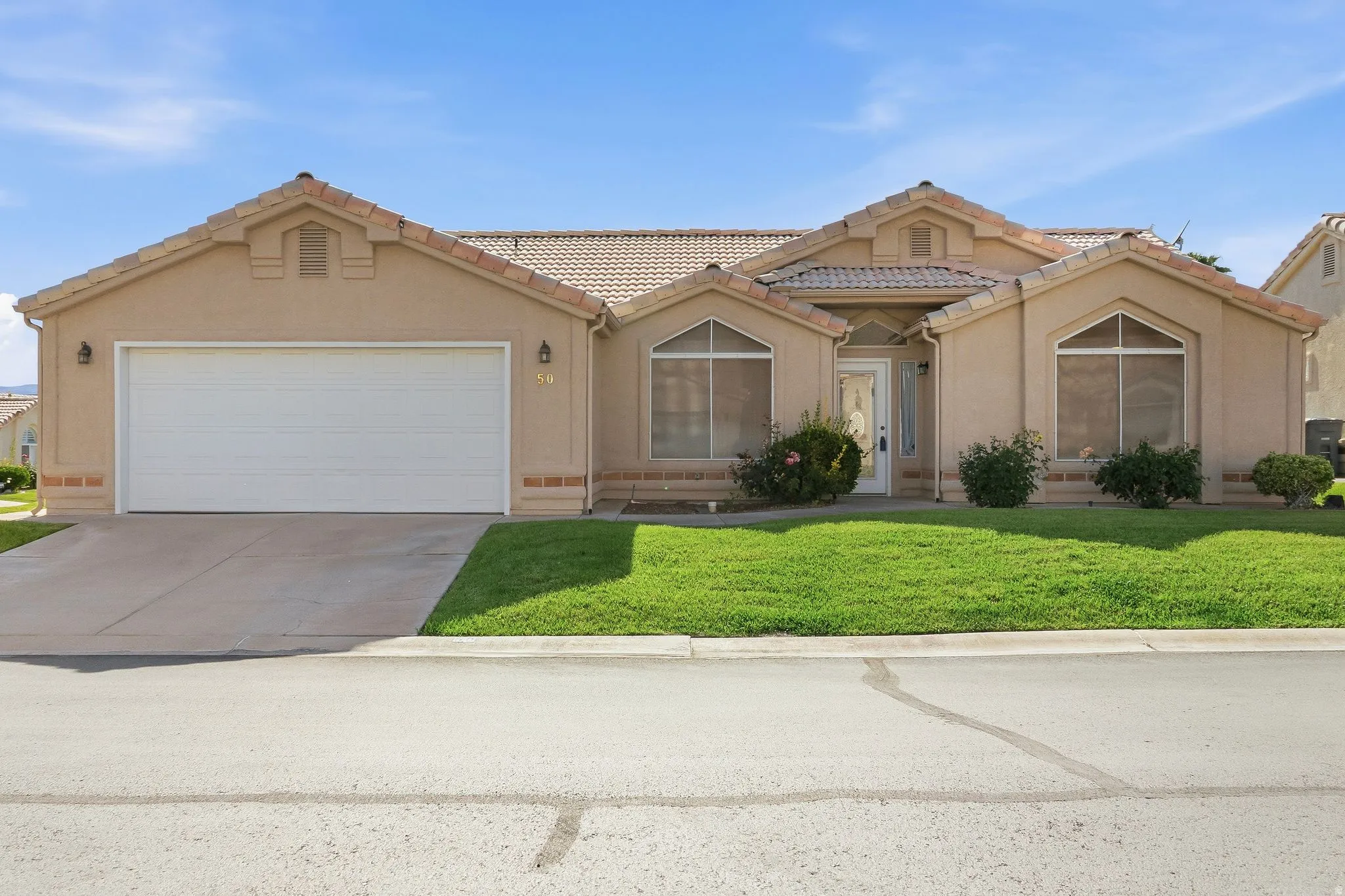 Stucco-finish residence with a tile roof, an integrated two-car garage, and a concrete driveway
