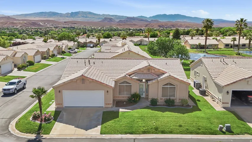 Single-story residence featuring a tile roof, an integrated garage, and a landscaped front yard with a palm tree