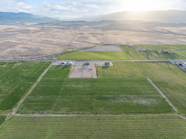 Expansive green fields featuring multiple buildings and mountainous terrain