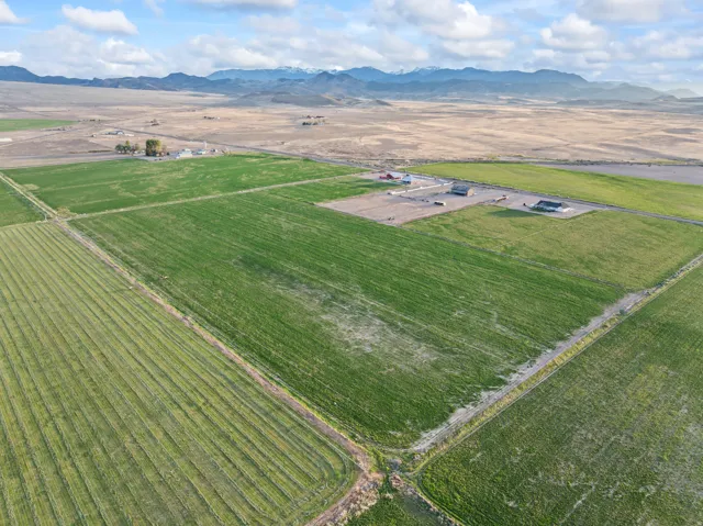 Expansive agricultural land featuring cultivated fields, a road, and distant mountains