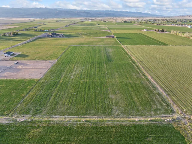 Expansive agricultural land featuring cultivated fields and open spaces, complemented by distant mountain ranges