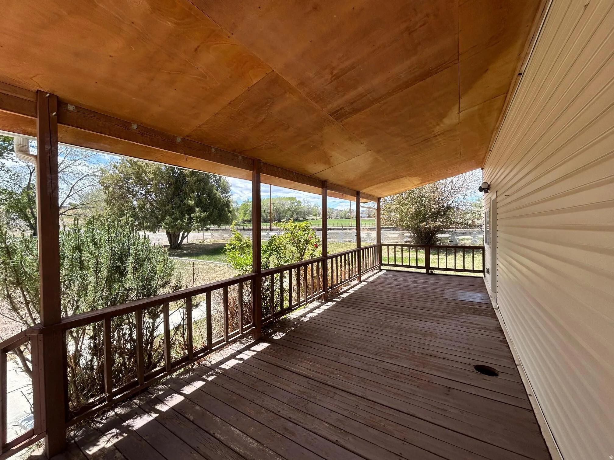 Expansive covered porch featuring wood-finish decking and a stained wood ceiling