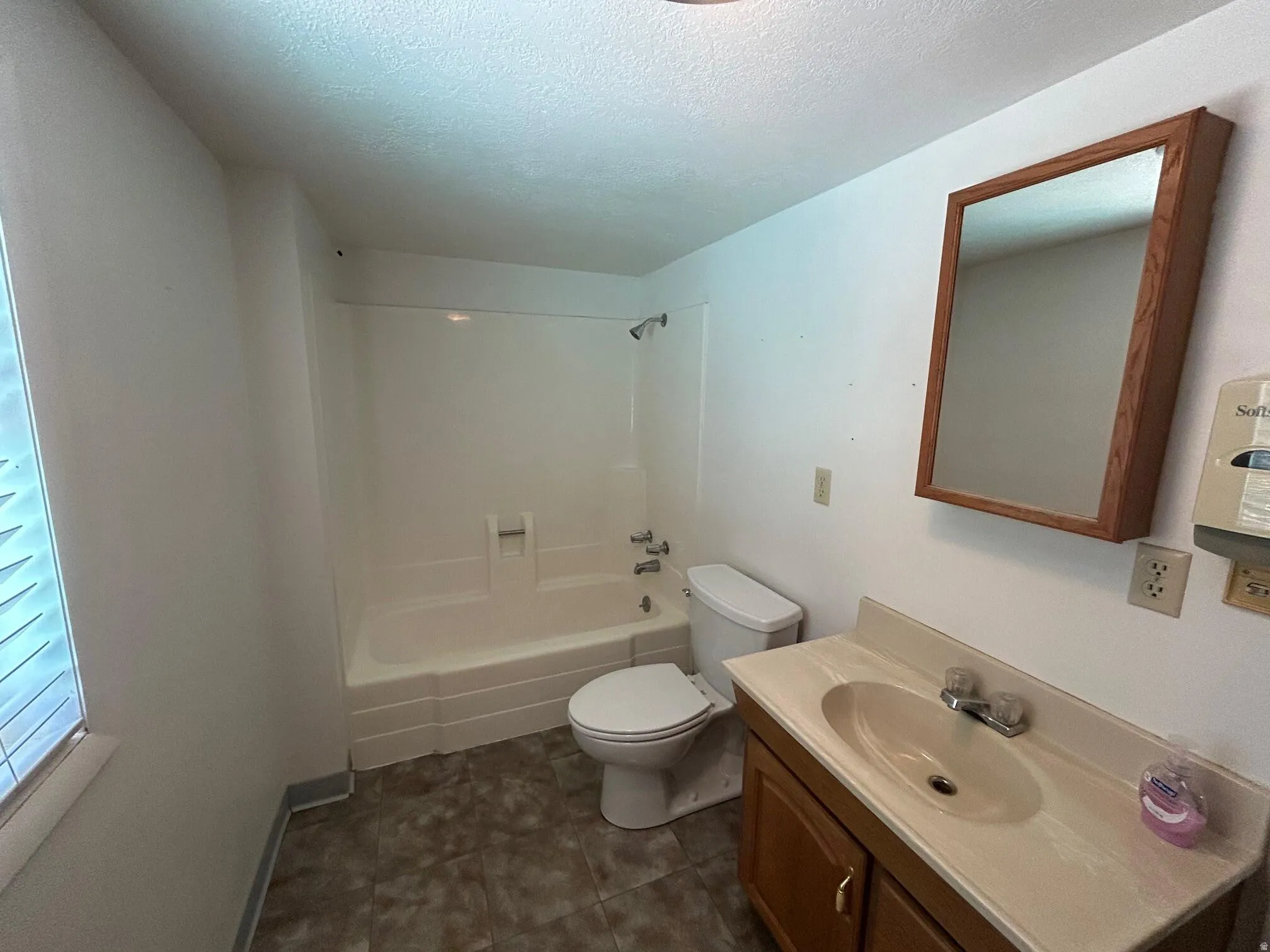 Full bathroom featuring a white tub/shower combination, white toilet, and a vanity with a built-in sink and wood-finish cabinetry