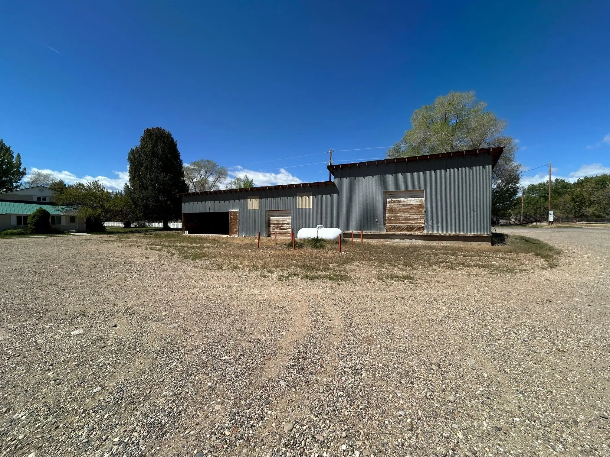 Corrugated metal-sided structure featuring a large open bay and two additional entry points