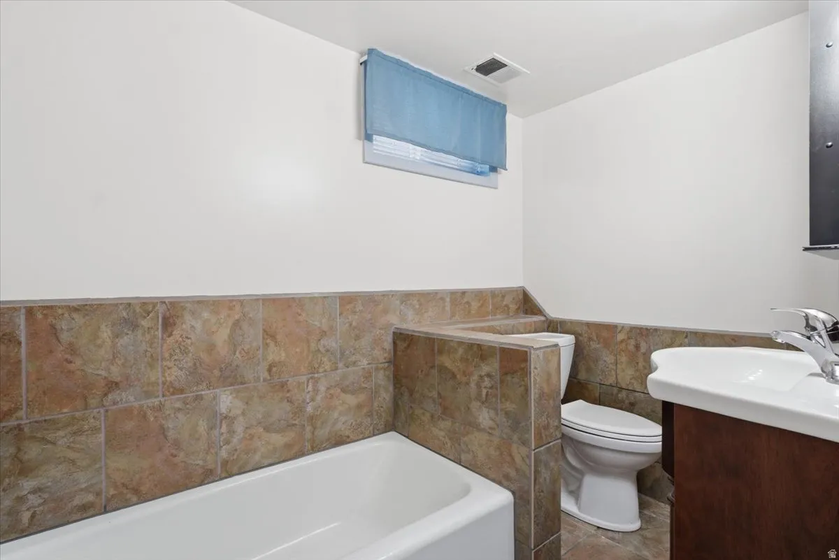 Bathroom with a white bathtub, toilet, and sink vanity