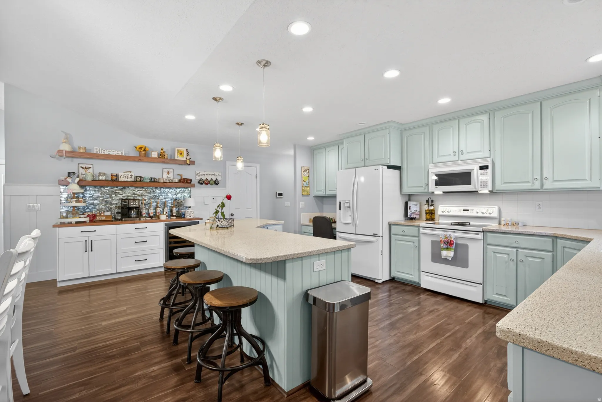 Spacious kitchen featuring wood-finish flooring, a central island with integrated seating, light blue cabinetry, and recessed lighting