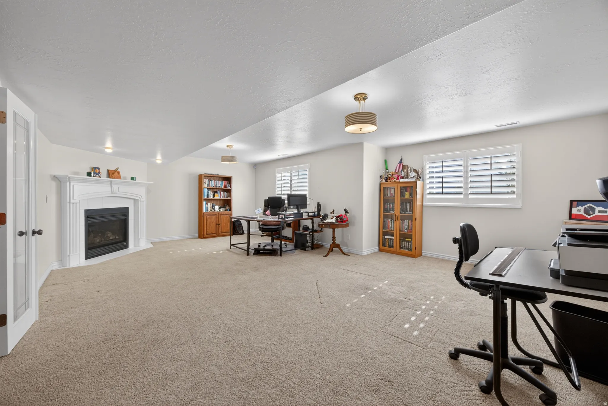 Spacious room featuring a white mantel fireplace, recessed lighting, and a drum pendant light fixture