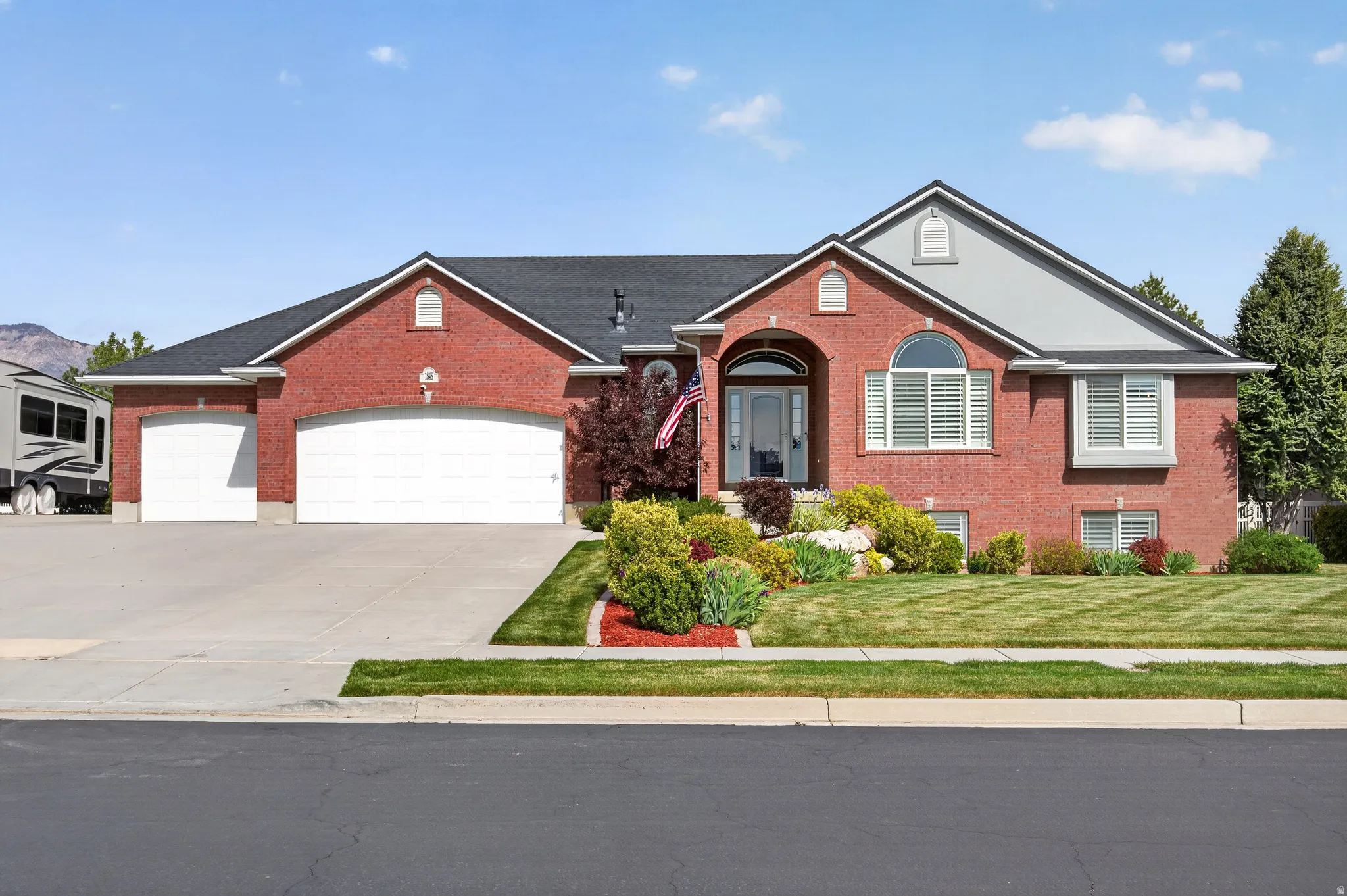 Red brick exterior featuring a multi-gabled roofline with dark shingles and light gray accents