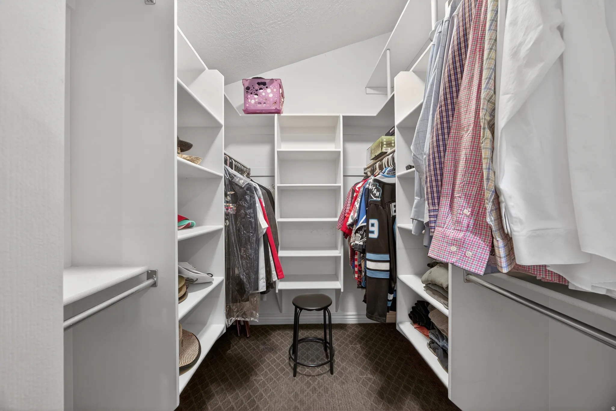 Custom closet system featuring multiple hanging rods, extensive shelving, and angled ceiling lines