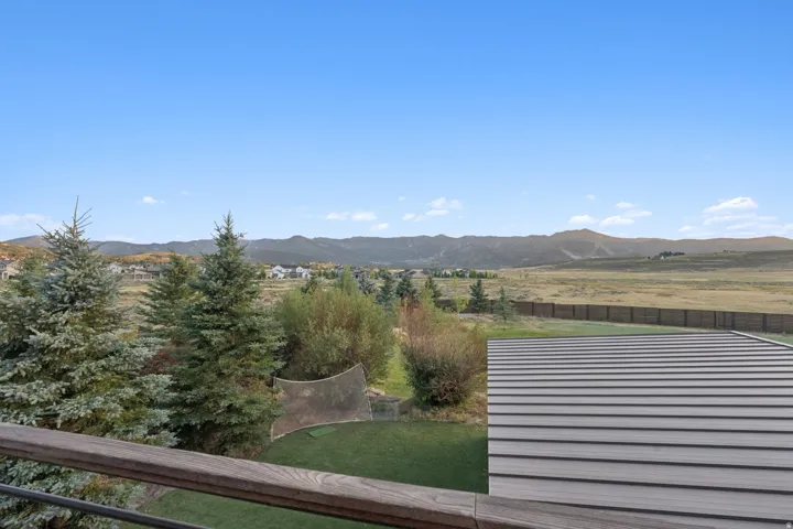 Expansive outdoor area featuring a wood-finish railing, composite decking, and distant mountain scenery
