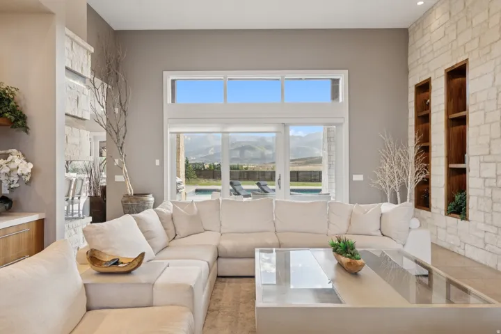 Spacious living area featuring high ceilings, stone accent walls with integrated shelving, and large windows with transom panels